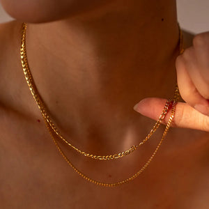 Gold dual-strand curb chain necklace with delicate links, styled on a woman's neck.