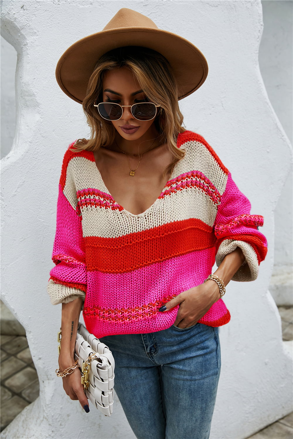 Deep plunge stripe knit pullover sweater in pink, red, and cream acrylic with long sleeves.