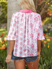 Maternity shirt with pink floral and bow pattern, ruffled sleeves, and pink collar.