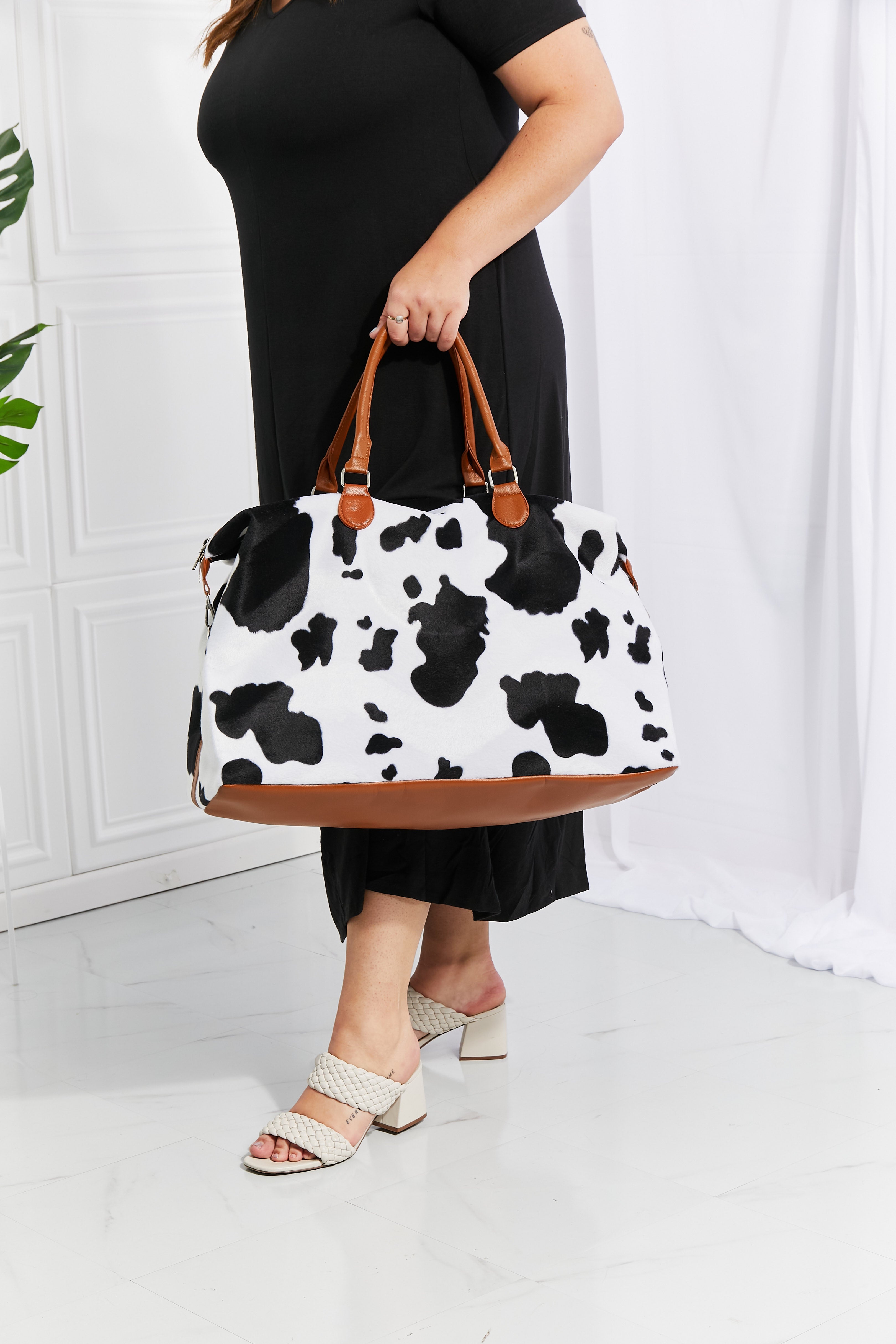 Cowhide print duffel bag with brown trim and handles
