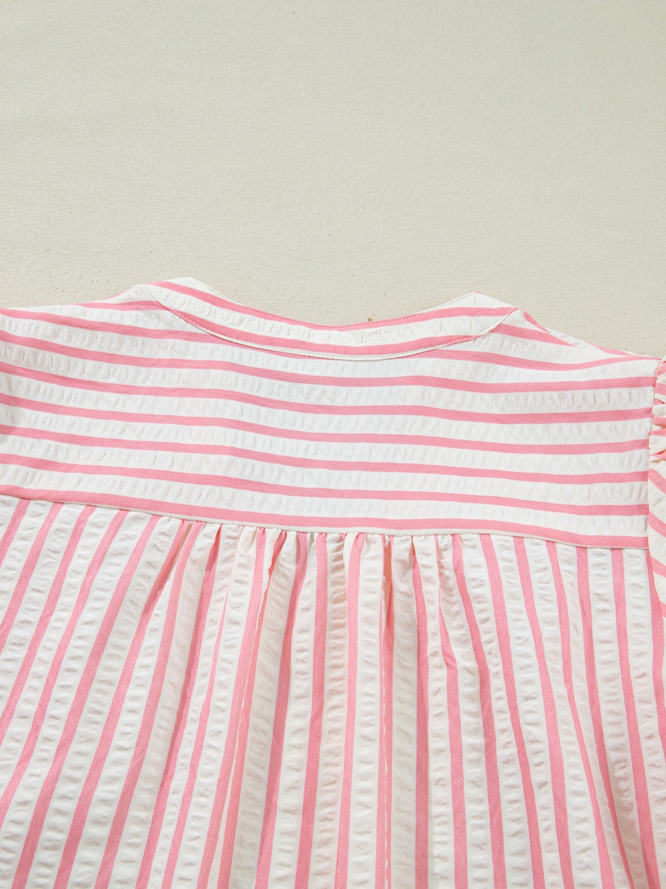 Pink and white striped textured blouse with gathered yoke and puff sleeves.