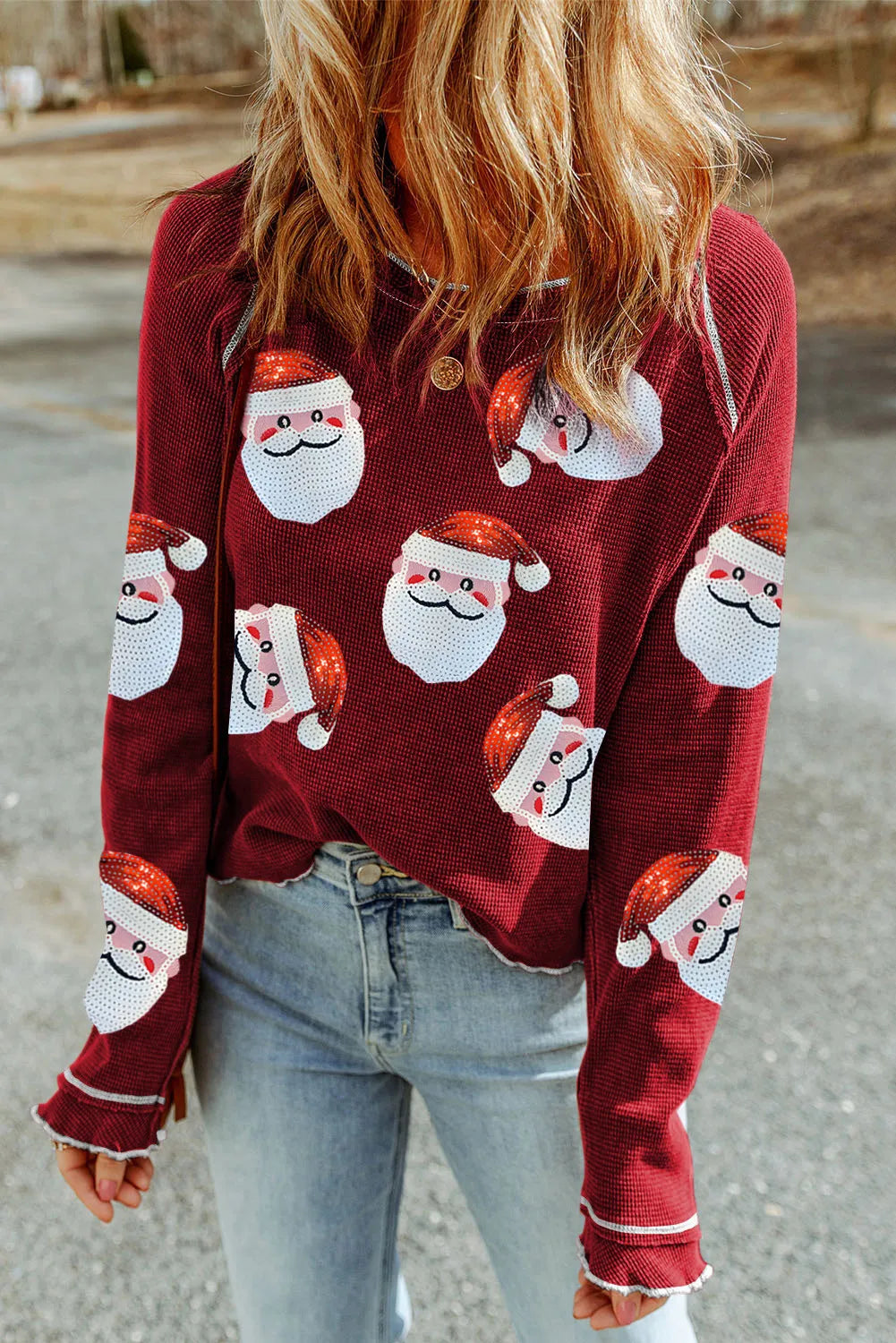 Scarlet waffle knit top with sequin Santa faces, crew neck, long sleeves, and ruffled cuffs.