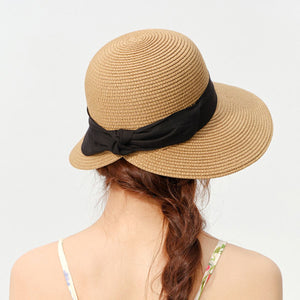 Woven straw wide brim sun hat in beige with black ribbon detail.