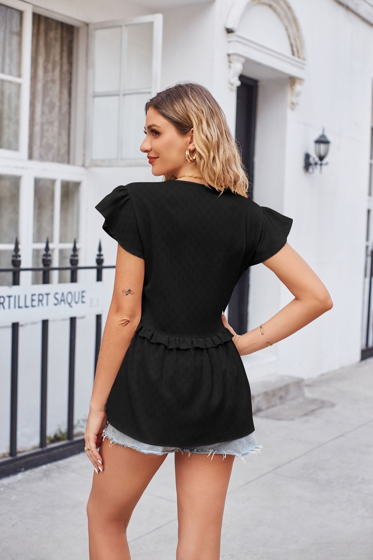 Black flutter sleeve peplum blouse with ruffled hem and subtle dot pattern