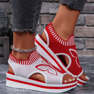 Red and white open-toe wedge sandals with butterfly motif mesh detail and striped trim.