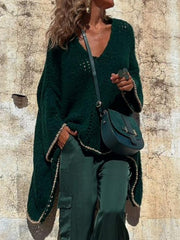 Dark green open knit sweater with asymmetric hem and beaded trim, styled with a crossbody bag.