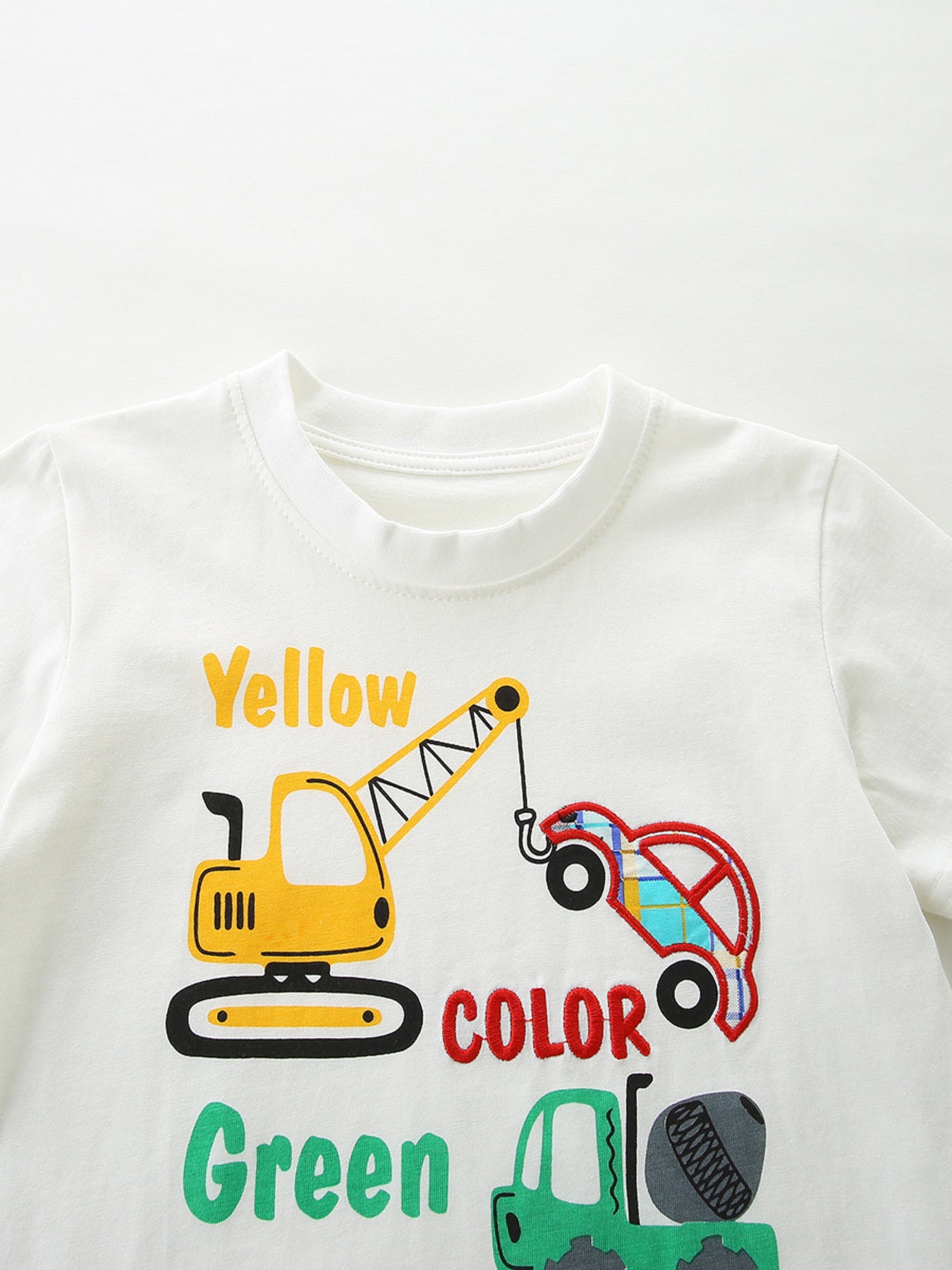 White cotton baby tee with playful construction vehicle graphic and colorful text.