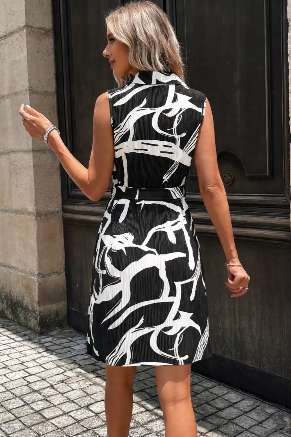 Black and white abstract print a-line dress with a belted waist and sleeveless design.