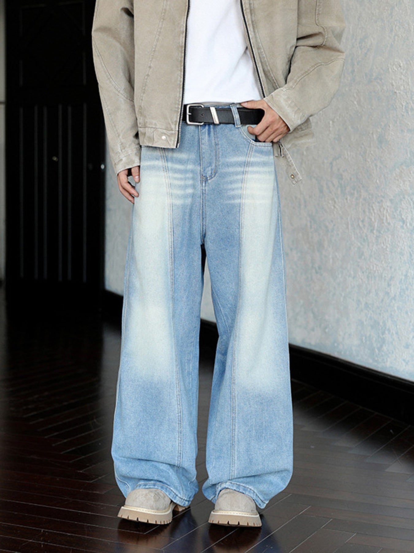Men's light blue wide leg jeans with faded detailing and a belted waist.