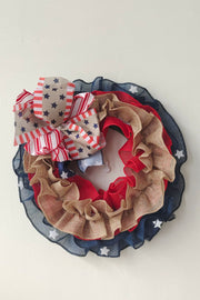 Patriotic ruffled burlap wreath with red, white, and blue stars and stripes bow.