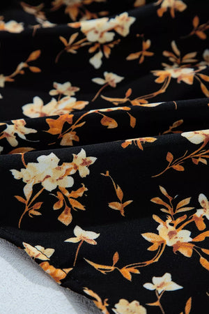 Black long-sleeve blouse with delicate floral print and smocked waist detail.