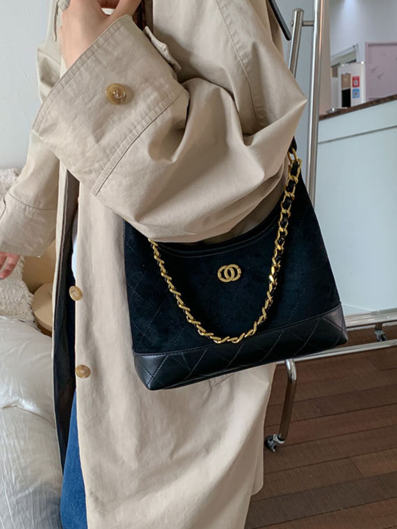 Black crossbody bag with quilted detail and gold chain strap.