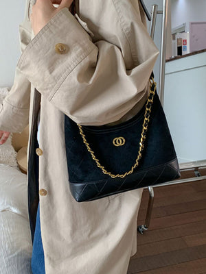 Black crossbody bag with quilted detail and gold chain strap.