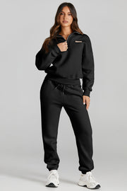 Black quarter-zip sweatshirt and jogger set with drawstring waist and a small logo patch.