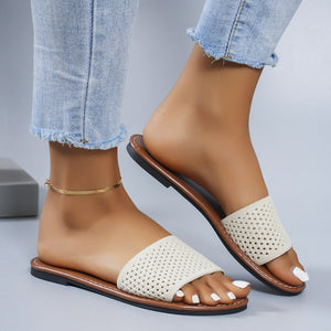 Perforated comfort slide sandals in beige with a brown sole and casual knit upper.