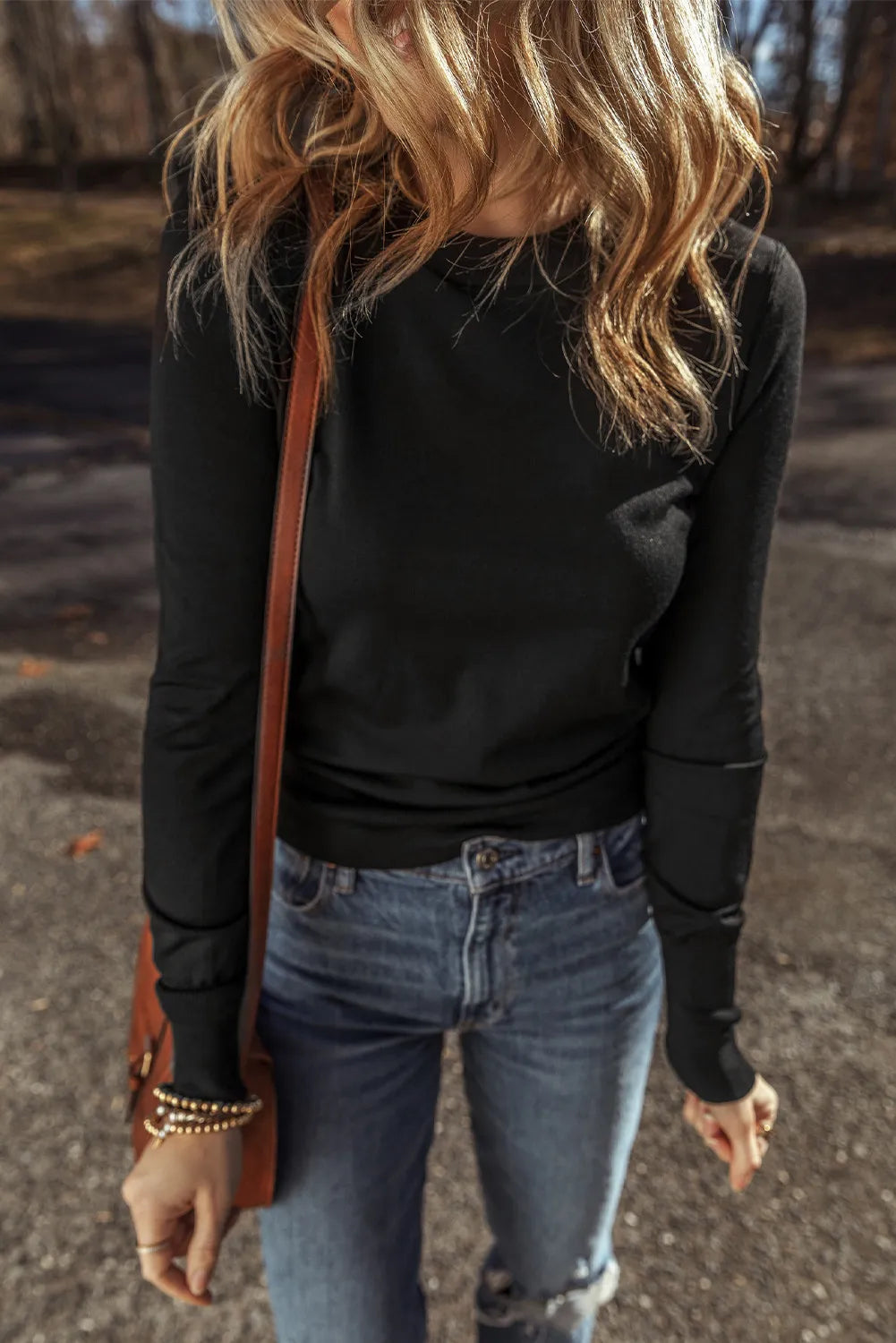 Black crewneck long sleeve knit top with subtle seam details on sleeves.