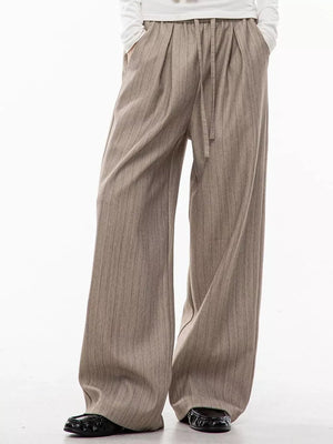 Khaki wide-leg pleated trousers with vertical pinstripes and drawstring waist.