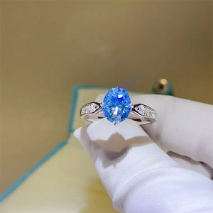 Sterling silver ring with oval blue moissanite and diamond halo accents.