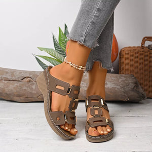 Brown open-toe wedge sandals with decorative gold buckles and cut-out details.