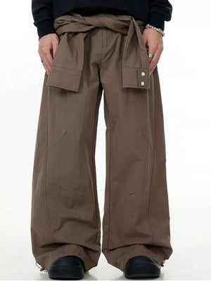 Brown wide-legged cargo pants with a tie waist and buttoned flap pockets.