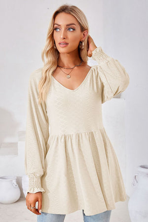 Cream textured babydoll blouse with V-neck and smocked cuffs.