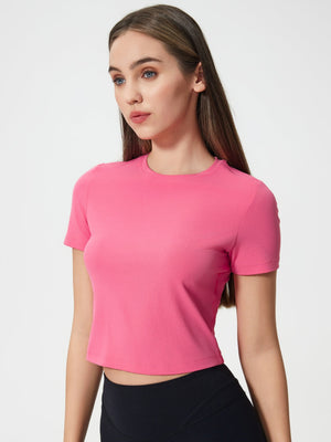 Fuchsia pink cropped performance crew neck top with short sleeves.