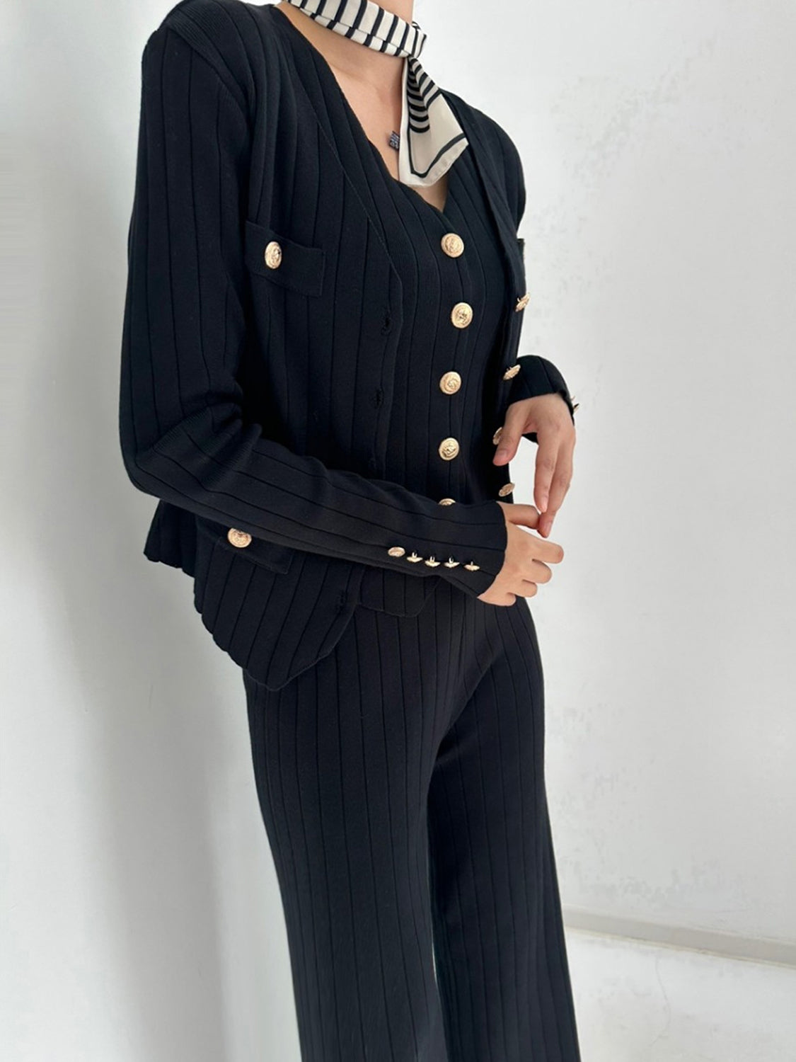 Black ribbed knit cardigan set with gold buttons and matching pants.