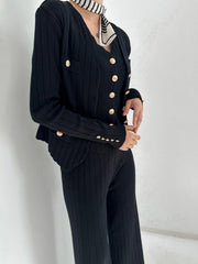 Black ribbed knit cardigan set with gold buttons and matching pants.