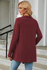 Burgundy textured knit cardigan with asymmetrical hem and long sleeves.