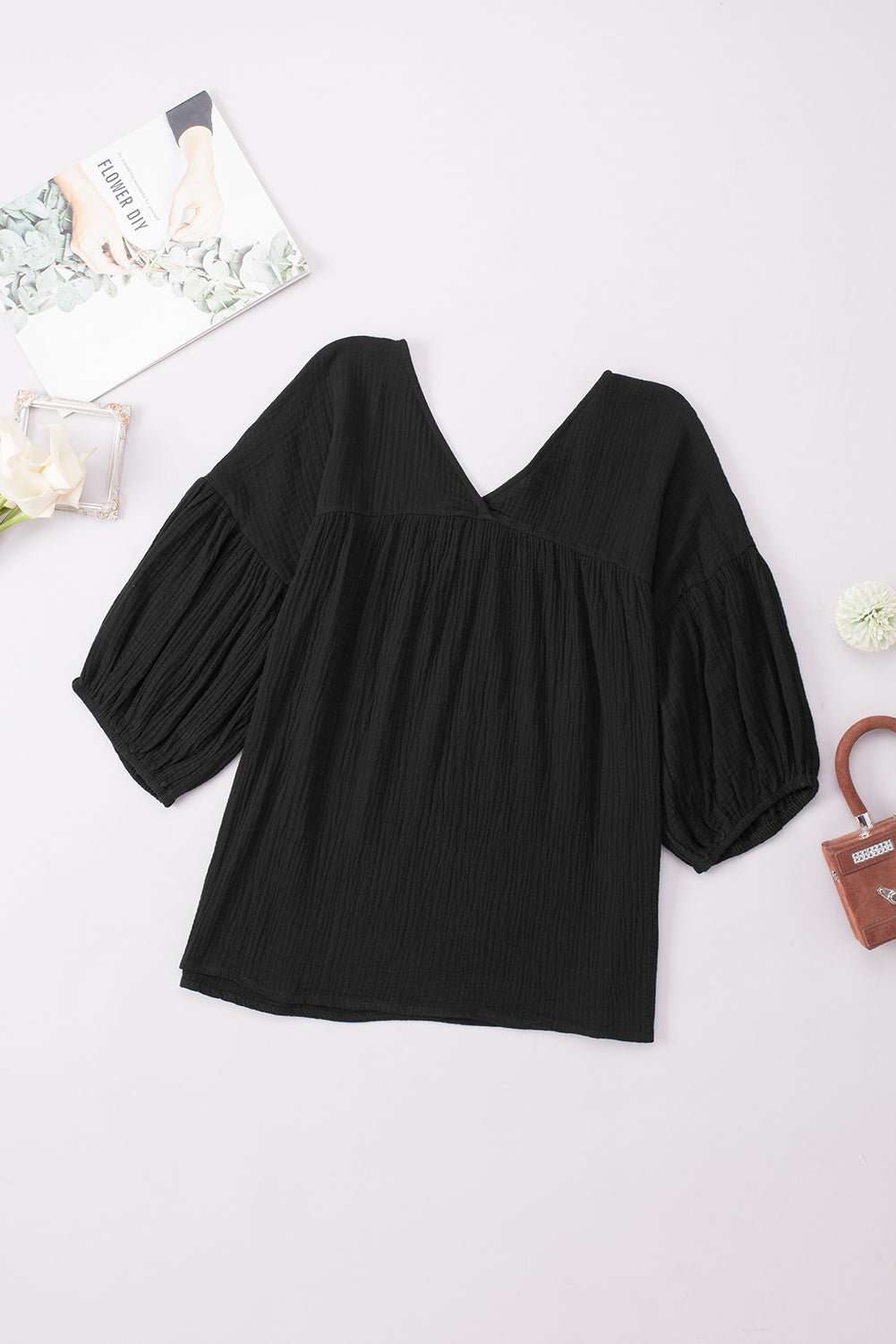 Black textured gauze blouse with V-neck and gathered puff sleeves.