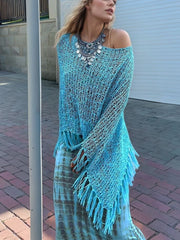 Sky blue open-knit acrylic boat neck poncho with fringe trim, styled with a statement necklace.