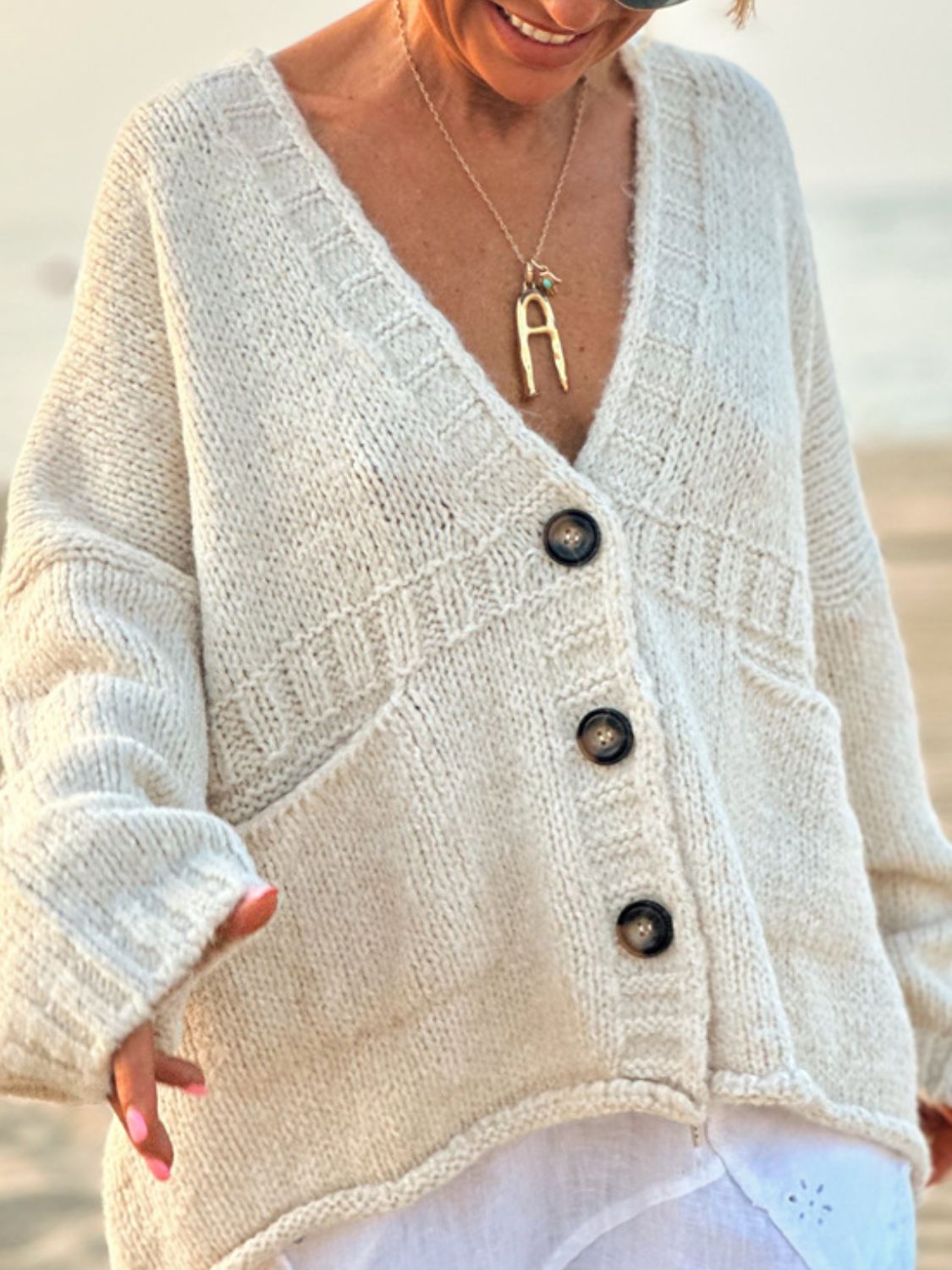 Beige bouclé knit oversized button-down cardigan with V-neck and pockets.