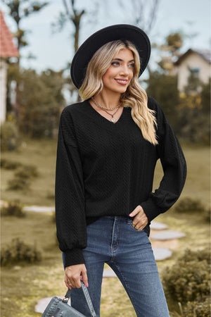 Black textured cable knit V-neck sweater with long sleeves and a relaxed fit.