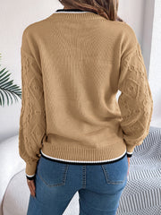Tan knit sweater with diamond texture on sleeves and contrast trim at neckline and hem.