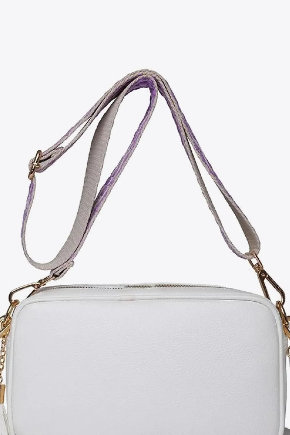White textured crossbody bag with purple and gray striped strap and tassel detail