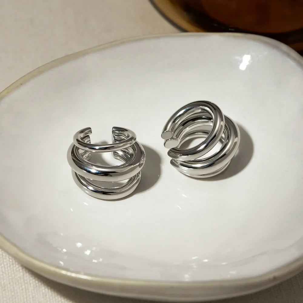 Sculptural silver ear cuff and hoop earrings with layered design.