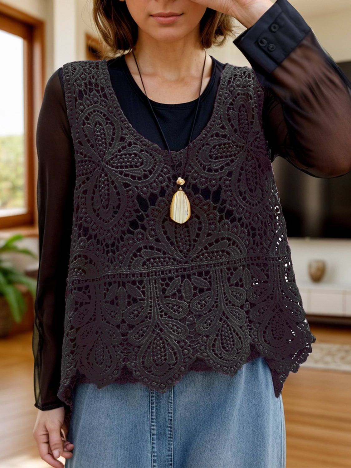 Black lace overlay cropped vest with intricate floral pattern and scalloped hem.