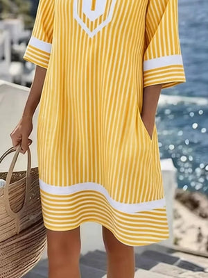 Yellow and white striped V-neck dress with pockets and white trim on sleeves and hem.