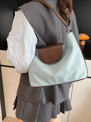 Chic canvas hobo crossbody bag in blue with brown trim and flap.