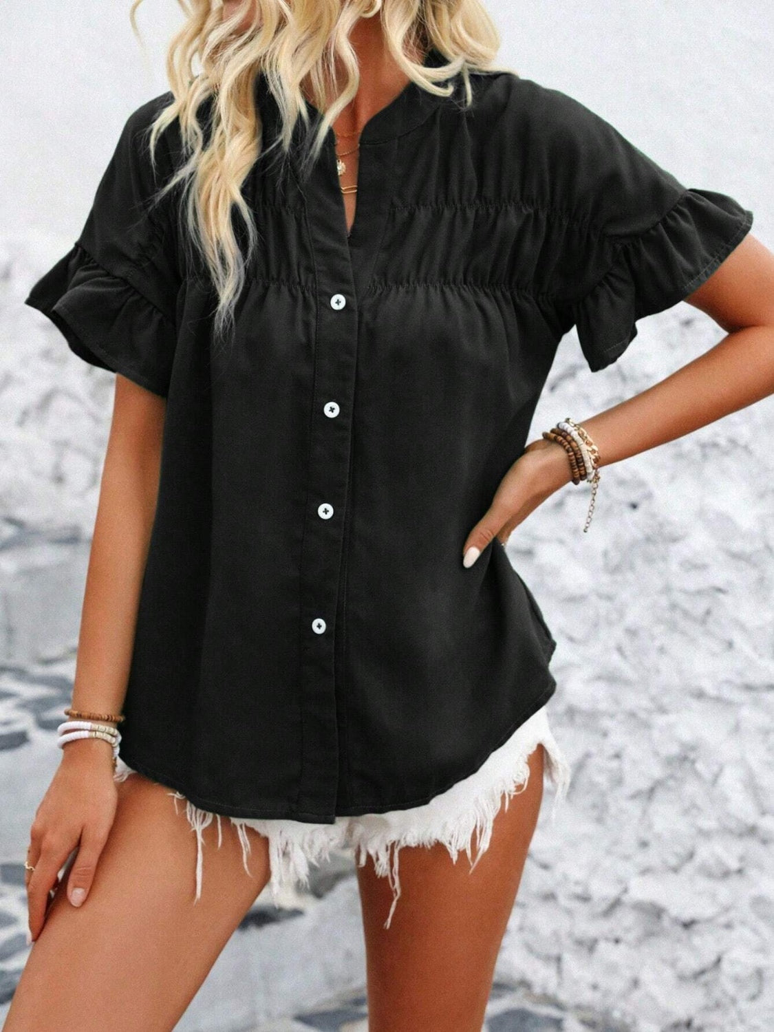 Black button-up blouse with gathered yoke and ruffle sleeves.