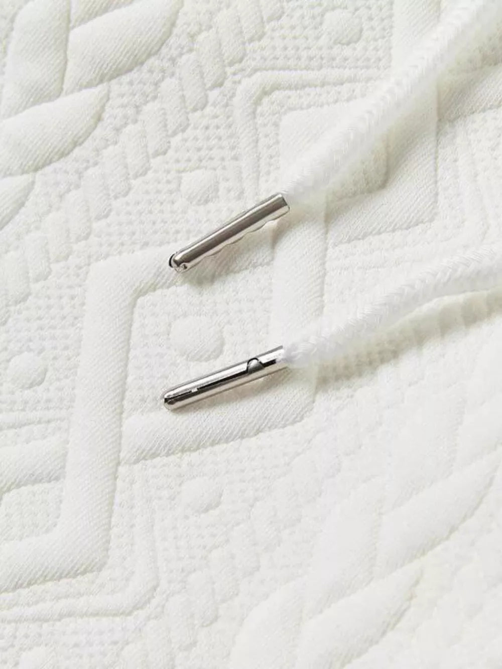 White knit shorts with textured pattern and silver-tipped drawstring.