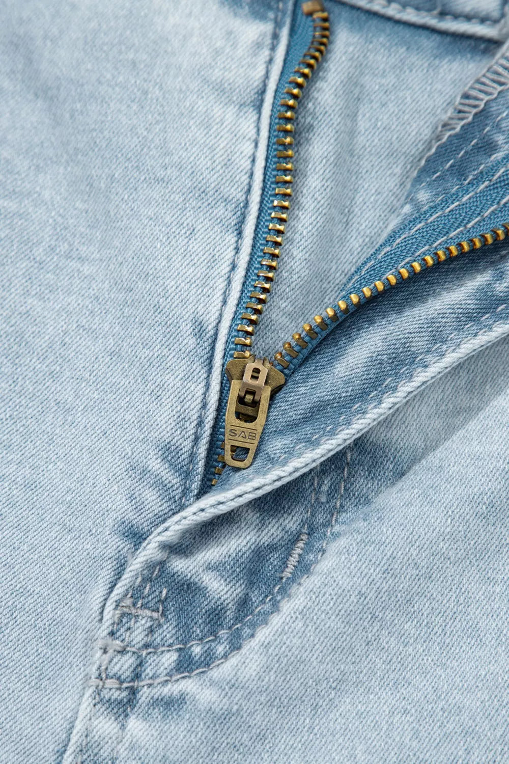 Light wash denim jeans with a brass zipper detail