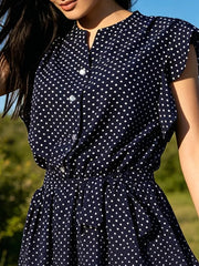 Navy polka dot dress with ruffle sleeves, button front, and tie waist detail.
