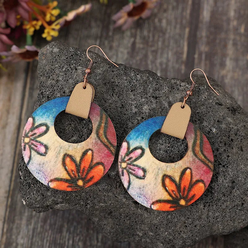 Painted floral wood hoop earrings with orange blooms and blue sky accents.