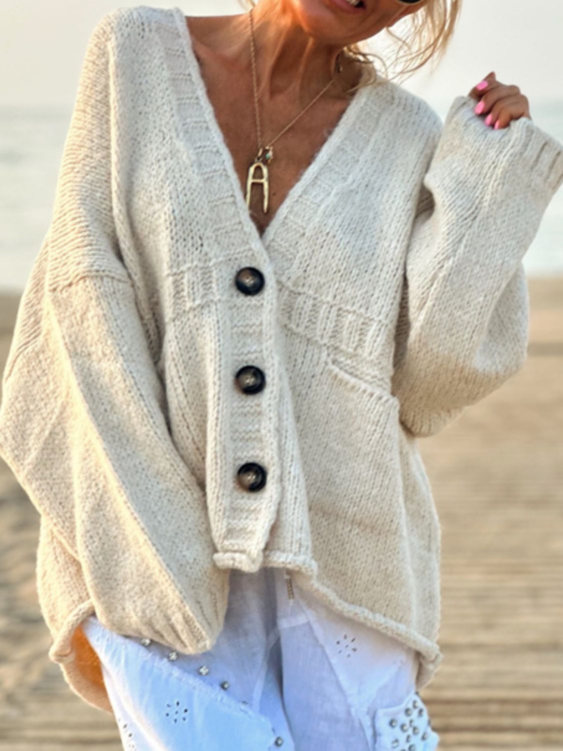 Beige bouclé oversized button-down cardigan with V-neck and textured knit details.