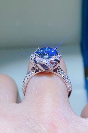 Blue moissanite halo ring with diamond band on finger