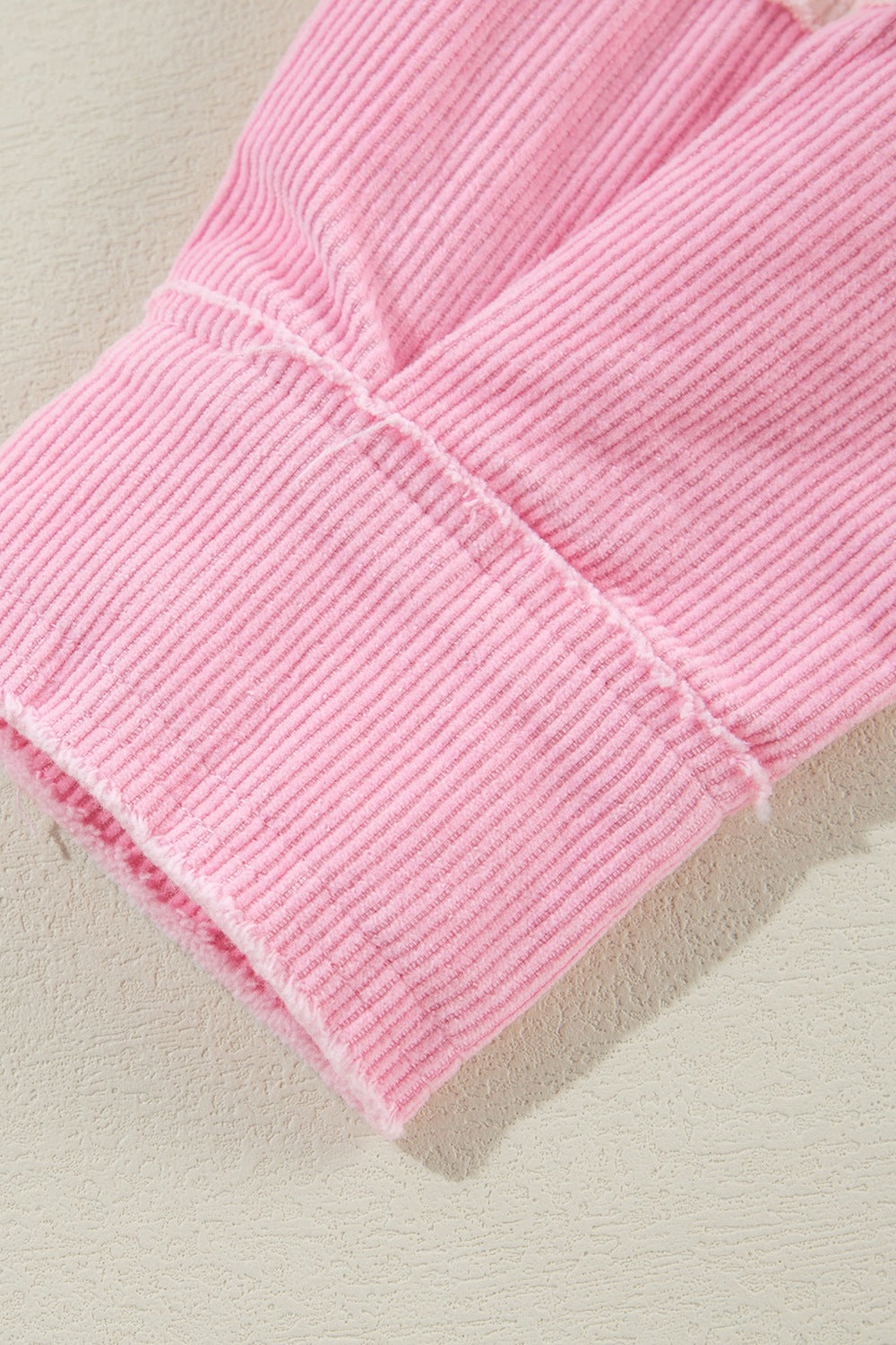 Blush pink corduroy shacket cuff with raw edge detail and visible stitching.