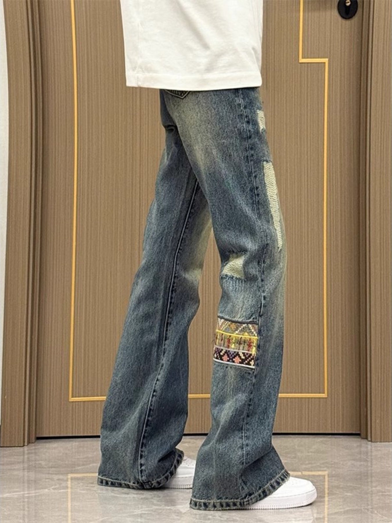 Distressed blue wash wide-leg jeans with patchwork details and distressed accents.
