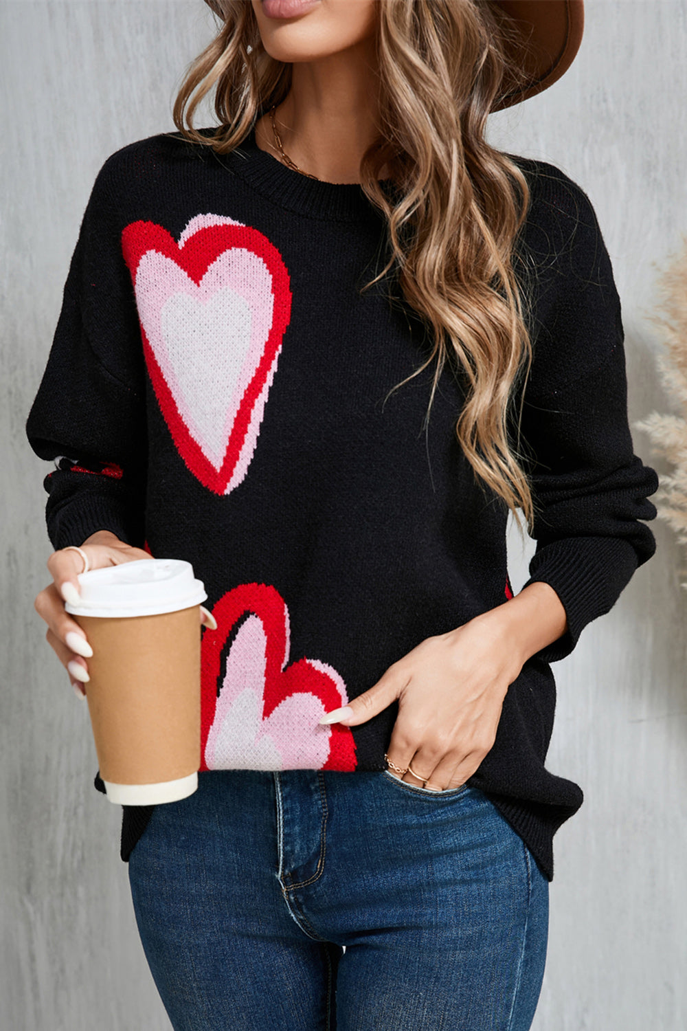 Black intarsia knit sweater with pink and red heart motif, crew neck, long sleeves.
