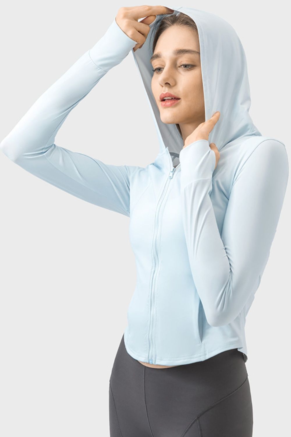 Light blue active hoodie with thumbholes and zipper closure, worn by a model.